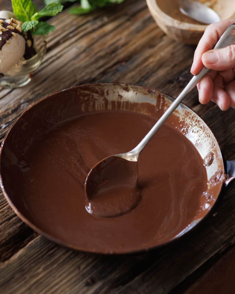spoon stirring pan of chocolate shell topping