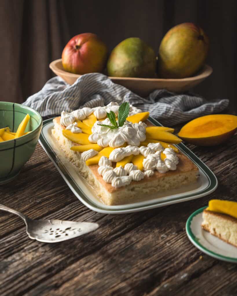 platter of mango tres leches cake with tray of fresh mangoes