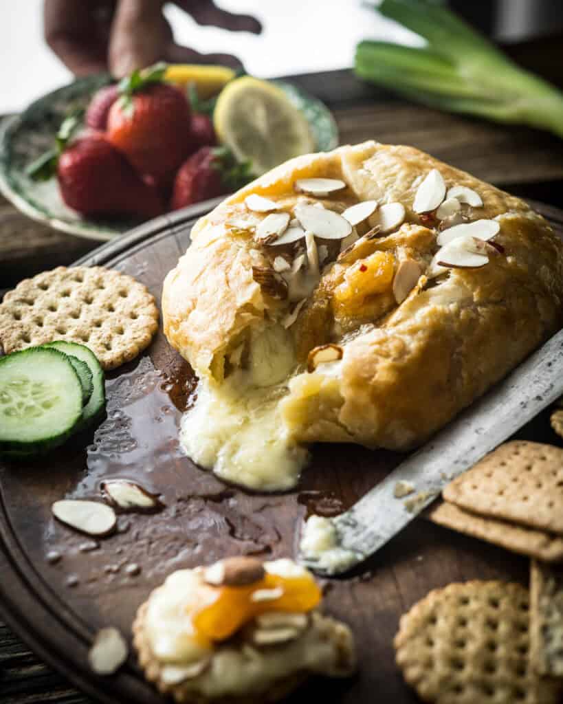 close up of baked brie with spicy peach jam melting on cutting board