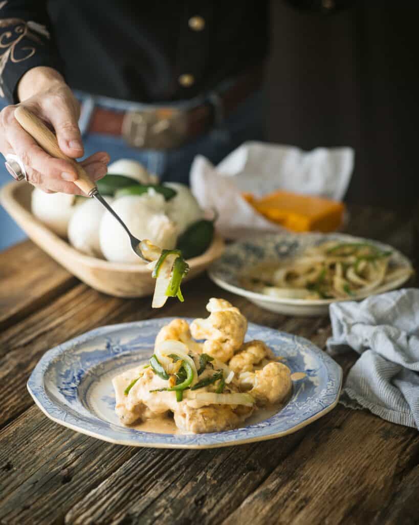 woman garnishing chicken with chiles