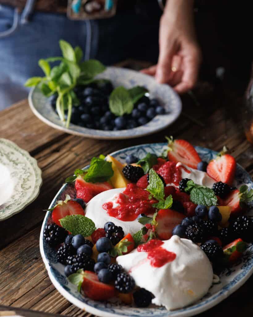 close up of honey smashed raspberries on summer pavlova platter